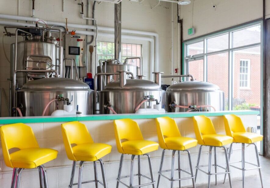 A row of yellow chairs in front of a bar.